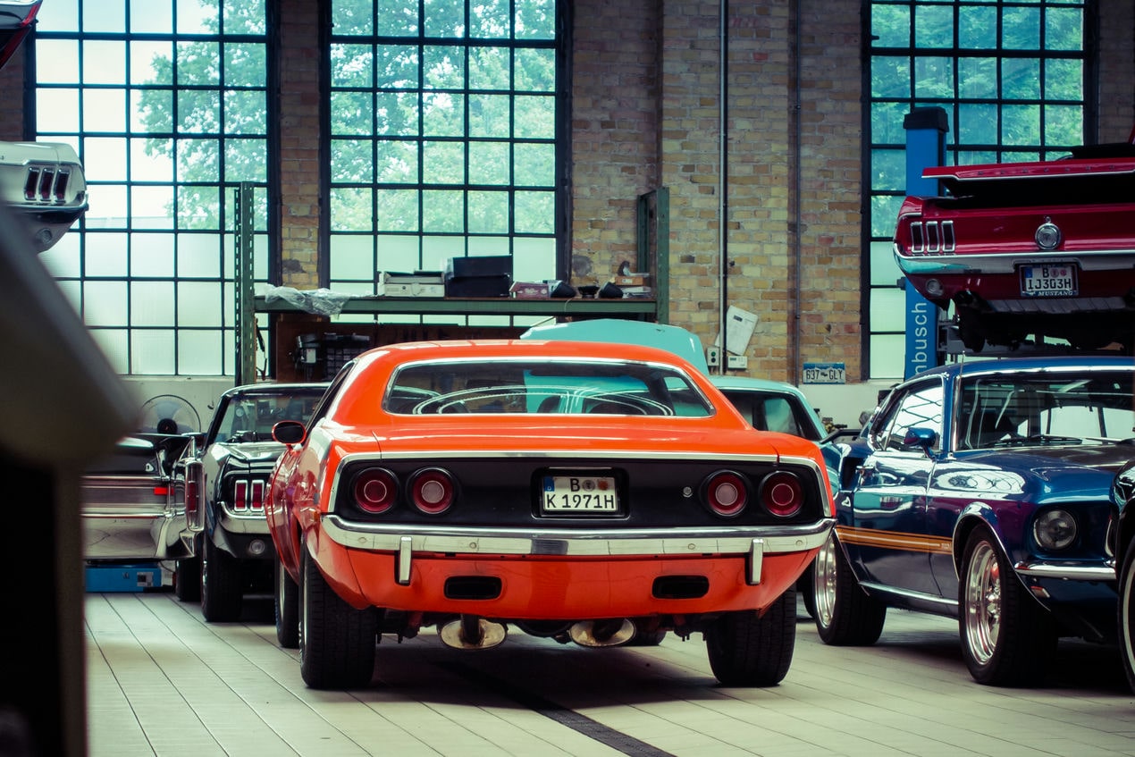 Plymonth Barracuda ao lado de um mustang em uma garagem