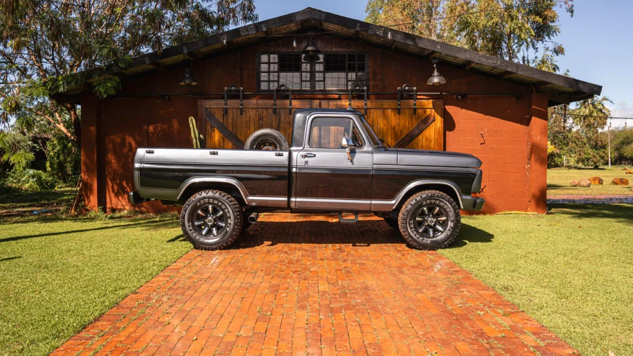 Perfil lateral da picape Ford F-1000 estacionada em cenário rústico