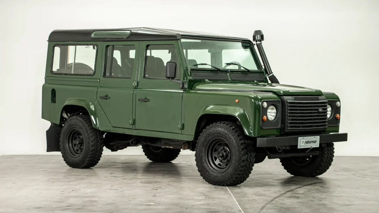 Land Rover Defender 110 verde clássico em estado de colecionador visto de perfil e frente