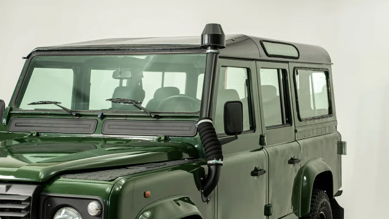 Detalhe do snorkel elevado, chapa xadrez no para-lama e janelas Alpine no teto do Land Rover Defender 110 verde