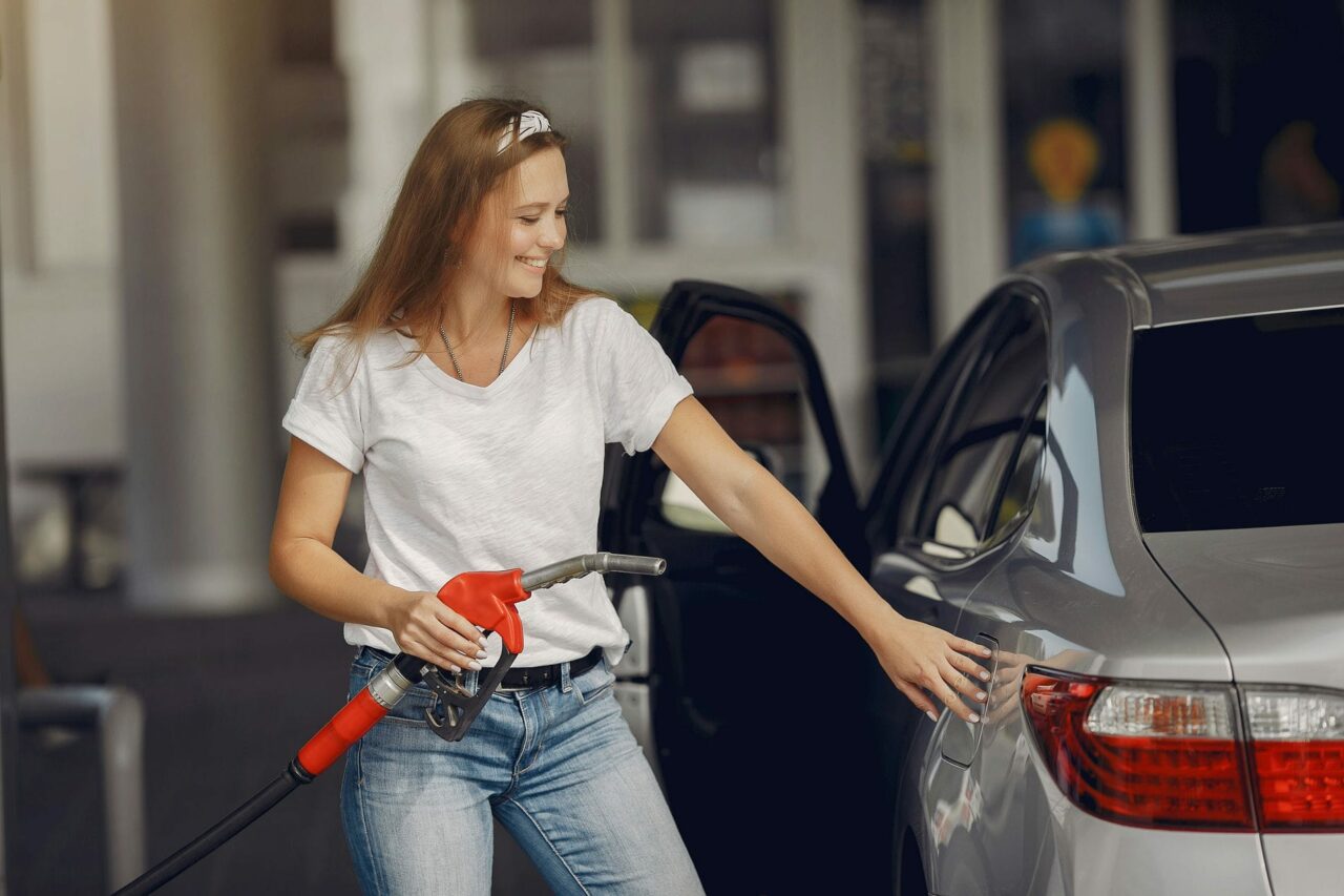 Mulher abastecendo um carro prata com combustível